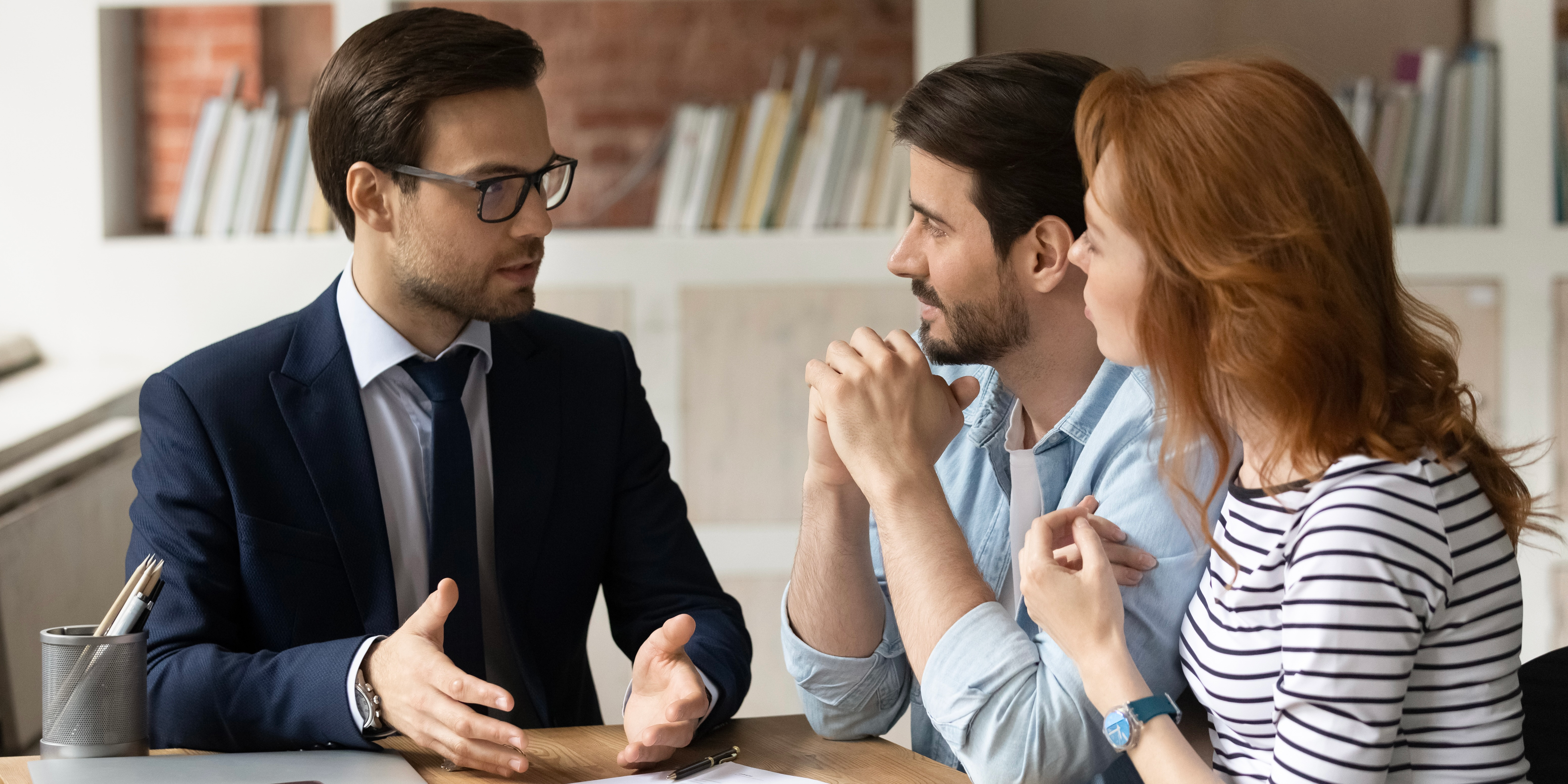 Asesor hipotecario ayudando a una pareja a elegir el mejor crédito y comprar su casa en preventa