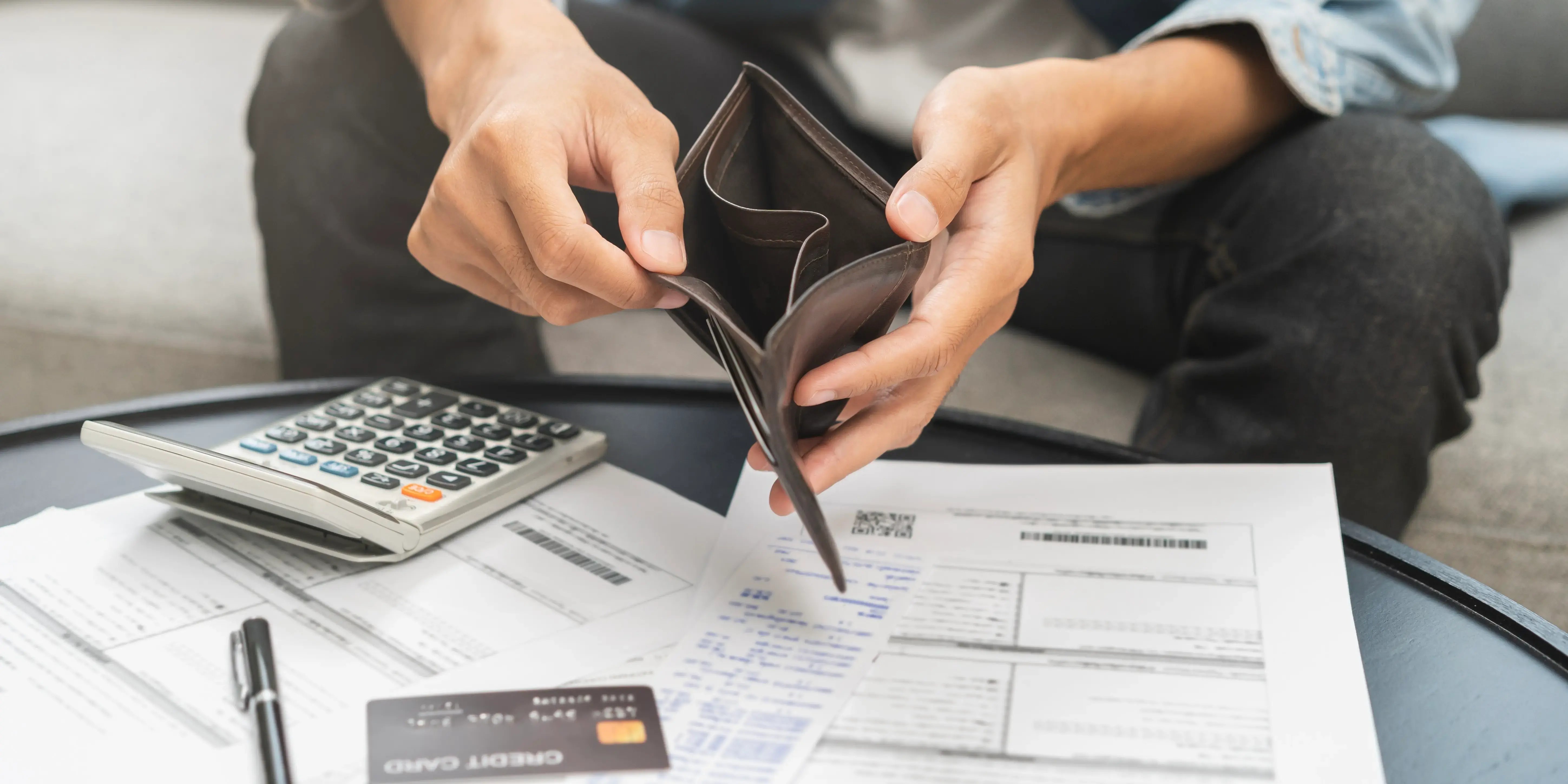Hombre agarrando su cartera con una tarjeta de crédito sobre la mesa pagando sus deudas para estar listo para comprar casa