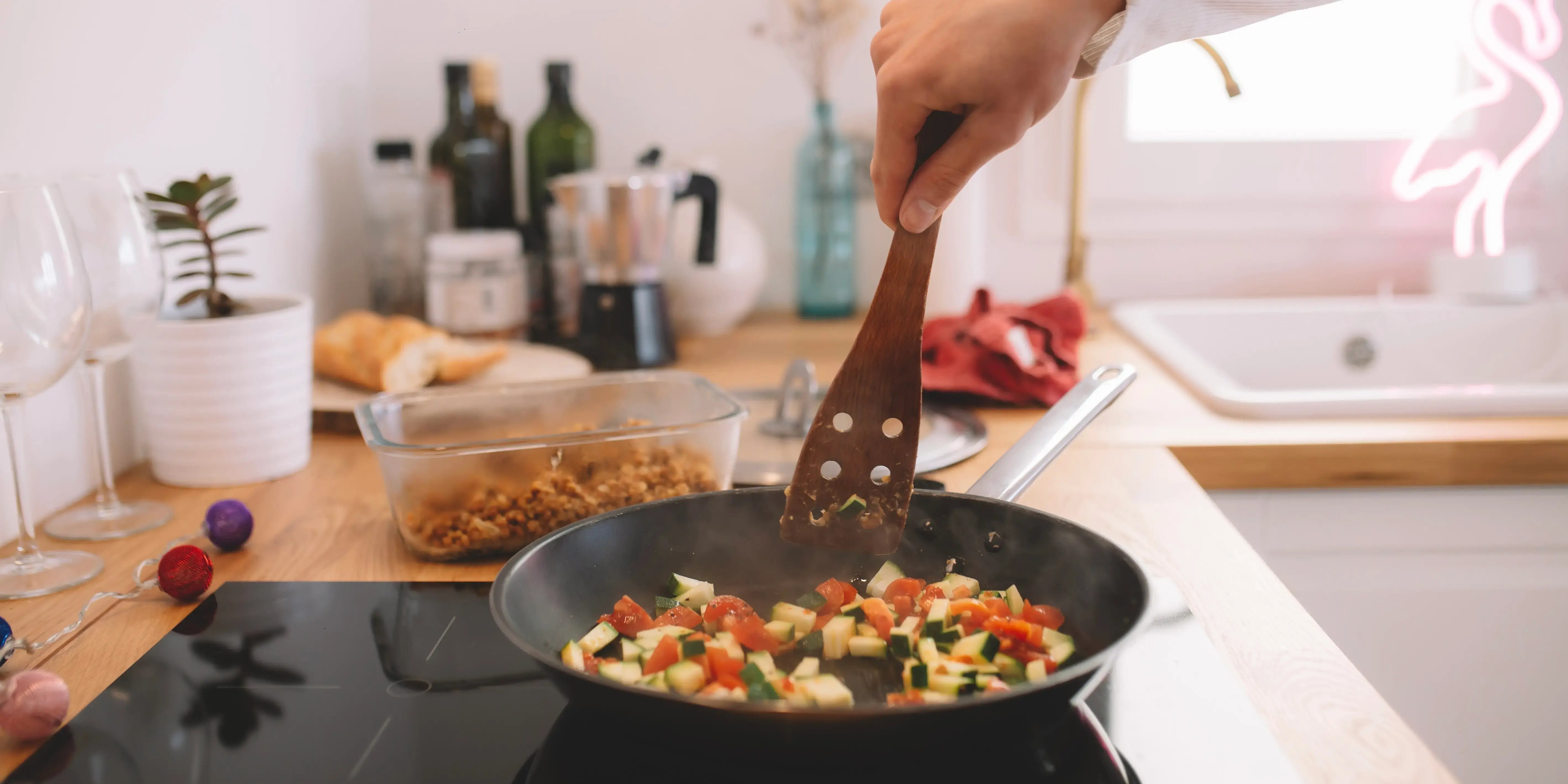 Hombre en la cocina con un sartén haciendo la comida pues dejó de vivir con roomies