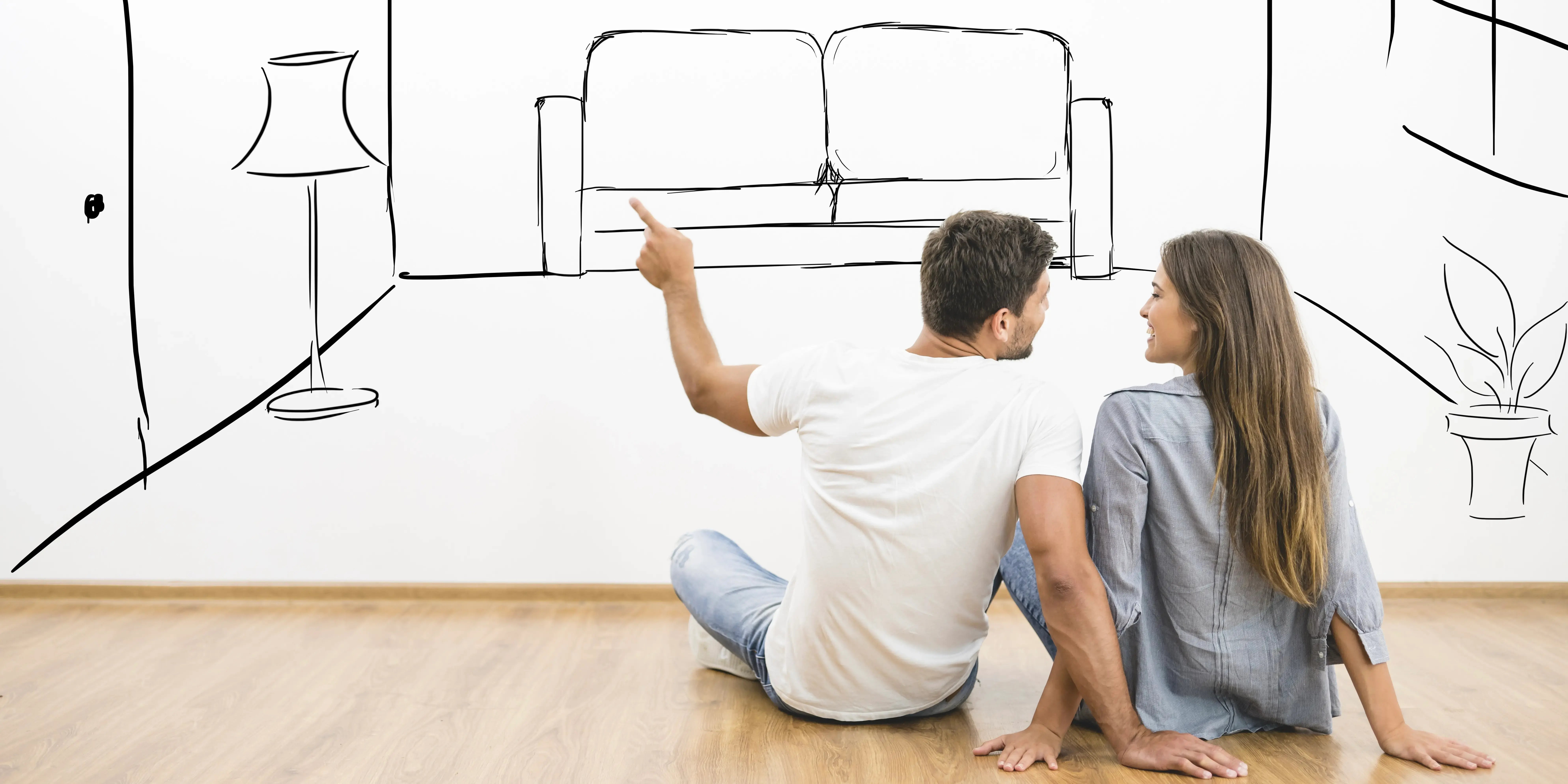 Hombre y mujer listos para comprar casa están sentados en el piso imaginando cómo se vería la sala dibujando un sillón un reloj y una meceta