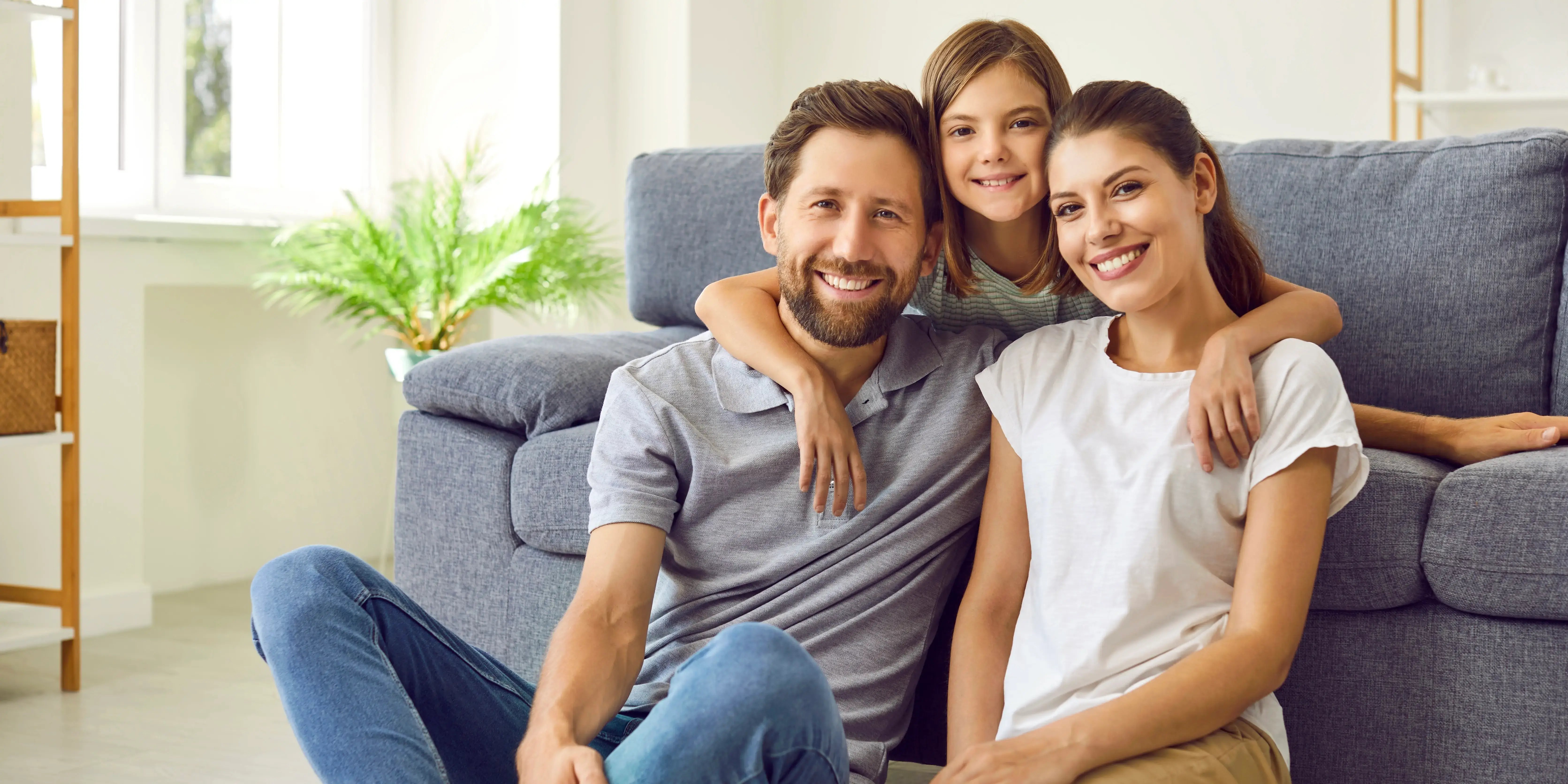 Linda hija abrazando a sus padres en el sofá que estuvieron listos para comprar casa