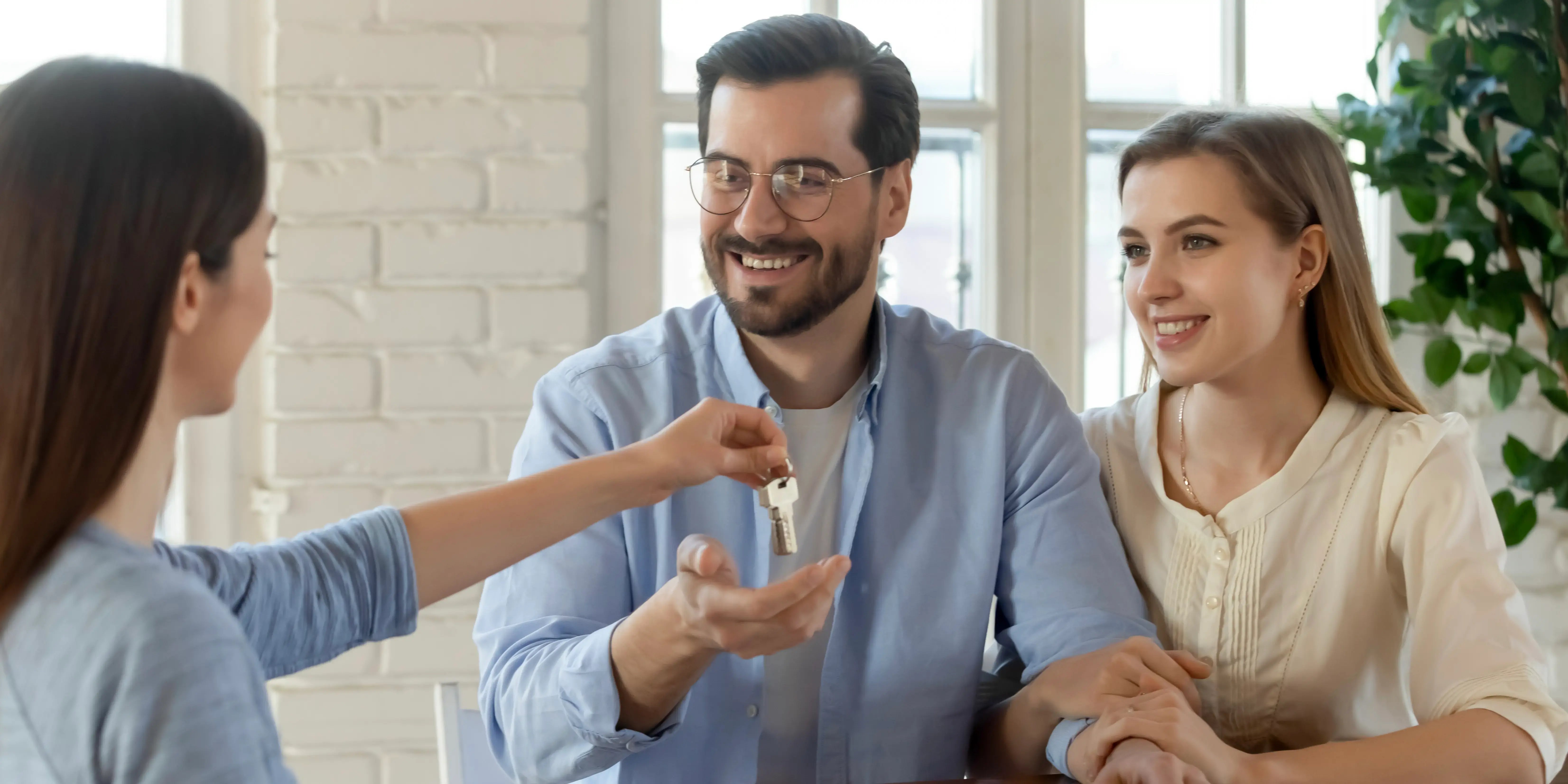 Una agente inmobiliario felicita a los cónyuges por la compra de su casa con un crédito compartido